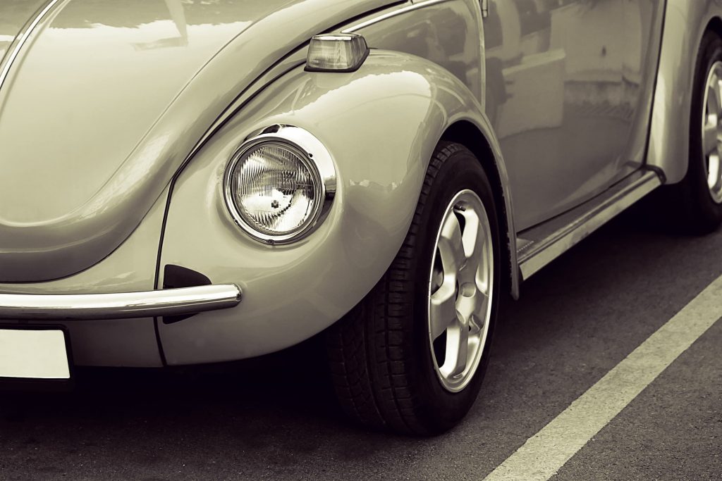 Close-up of a vintage retro car parked in a street with classic round headlight.